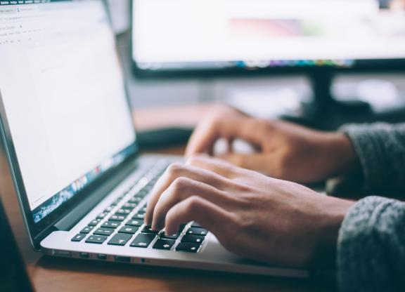 Hands typing on a laptop